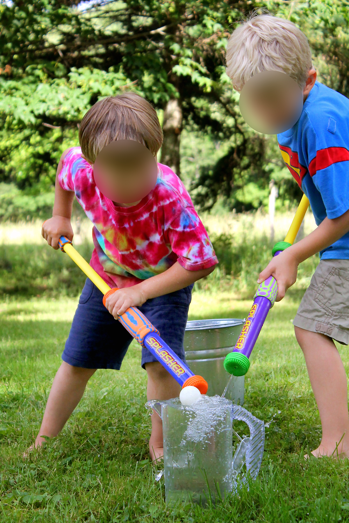 Two children using water blasters to fill a pitcher with water to float a ping pong ball during a cooperative backyard water game.