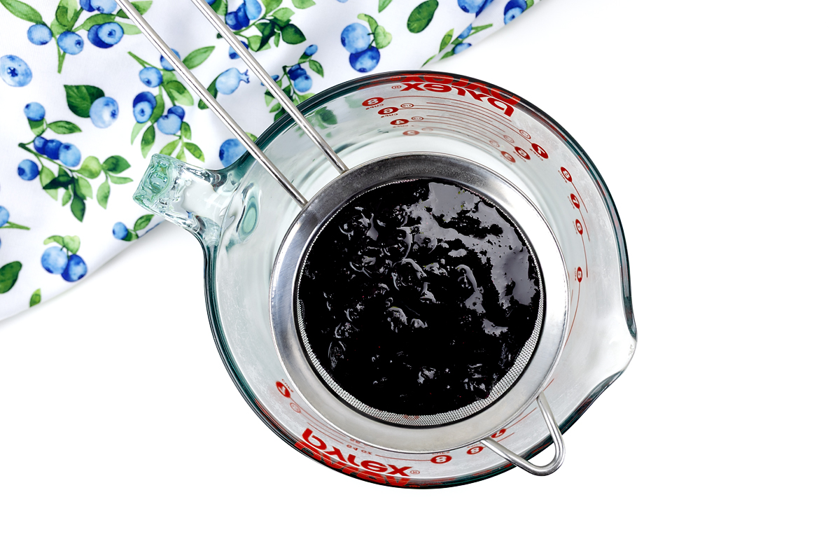 Blueberry syrup being strained into a bowl.
