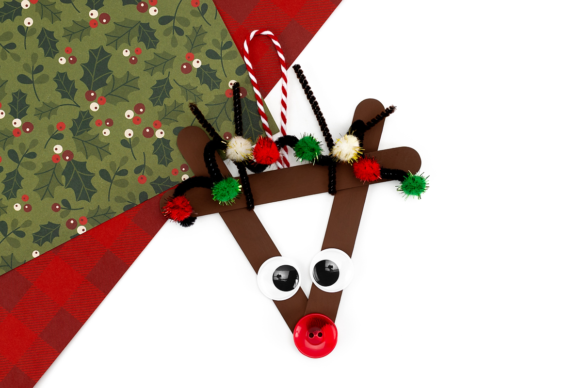 Reindeer ornament with black pipe cleaner spiral wrapped around antlers, decorated with sparkly red, green, and white pom-poms like Christmas lights.