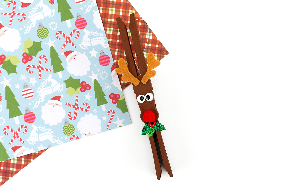 The clothespin reindeer ornament is decorated with felt antlers, eyes, nose, and a holly sticker.
