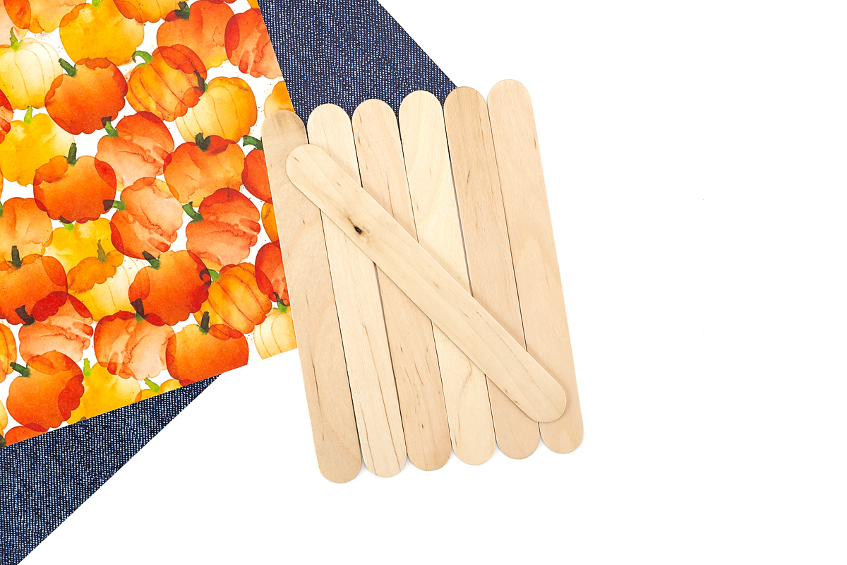 Gluing craft sticks together to form the base of a pumpkin keepsake.