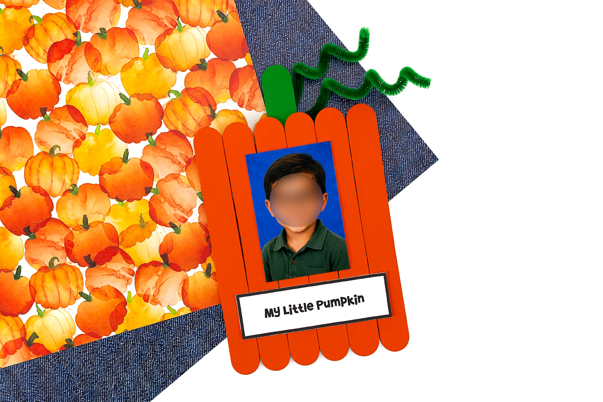 Finished popsicle stick pumpkin keepsake with photo, ready to hang on the fridge.