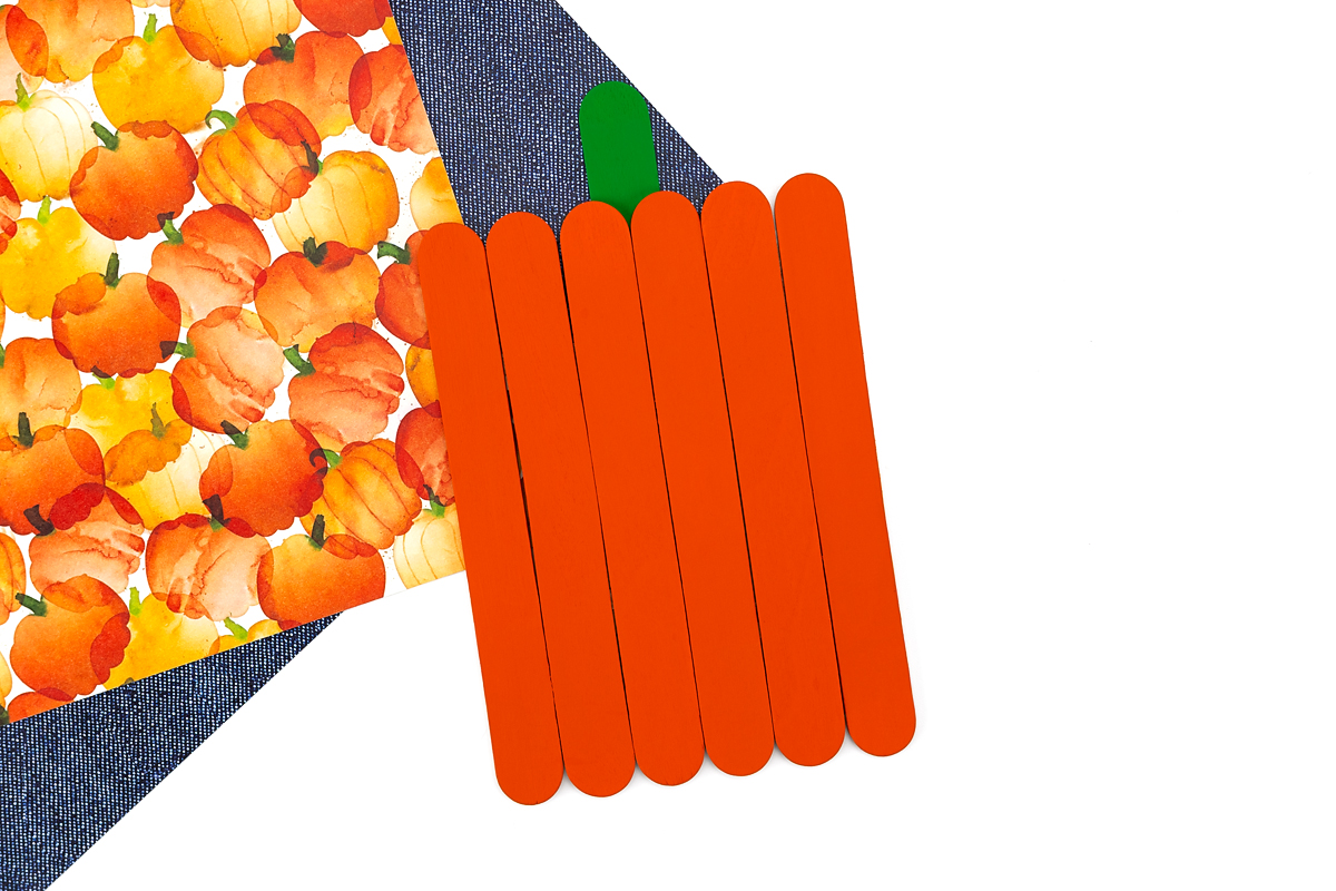 Popsicle stick pumpkin keepsake with a green craft stick stem glued to the back.
