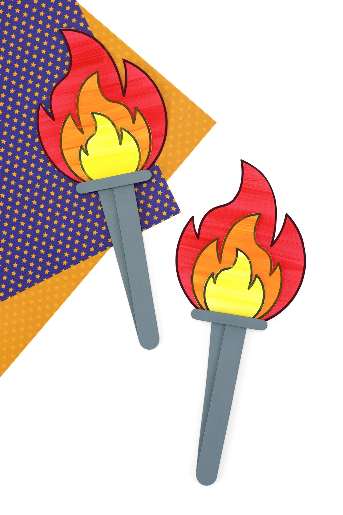 Close-up of the finished torch showing red, orange, and yellow paper flames layered on top of grey craft sticks.