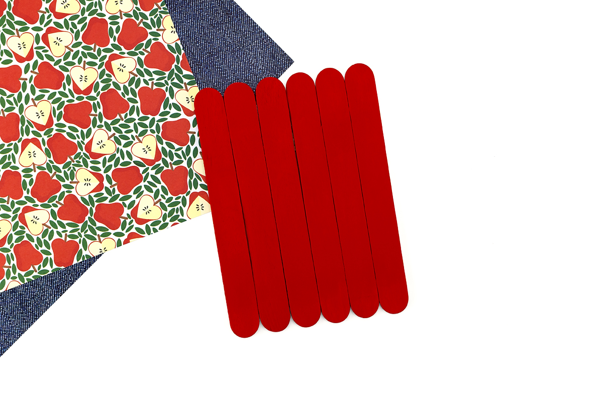 Six wide craft sticks painted red and glued together, the base of a popsicle stick apple craft before adding the stem and leaf.
