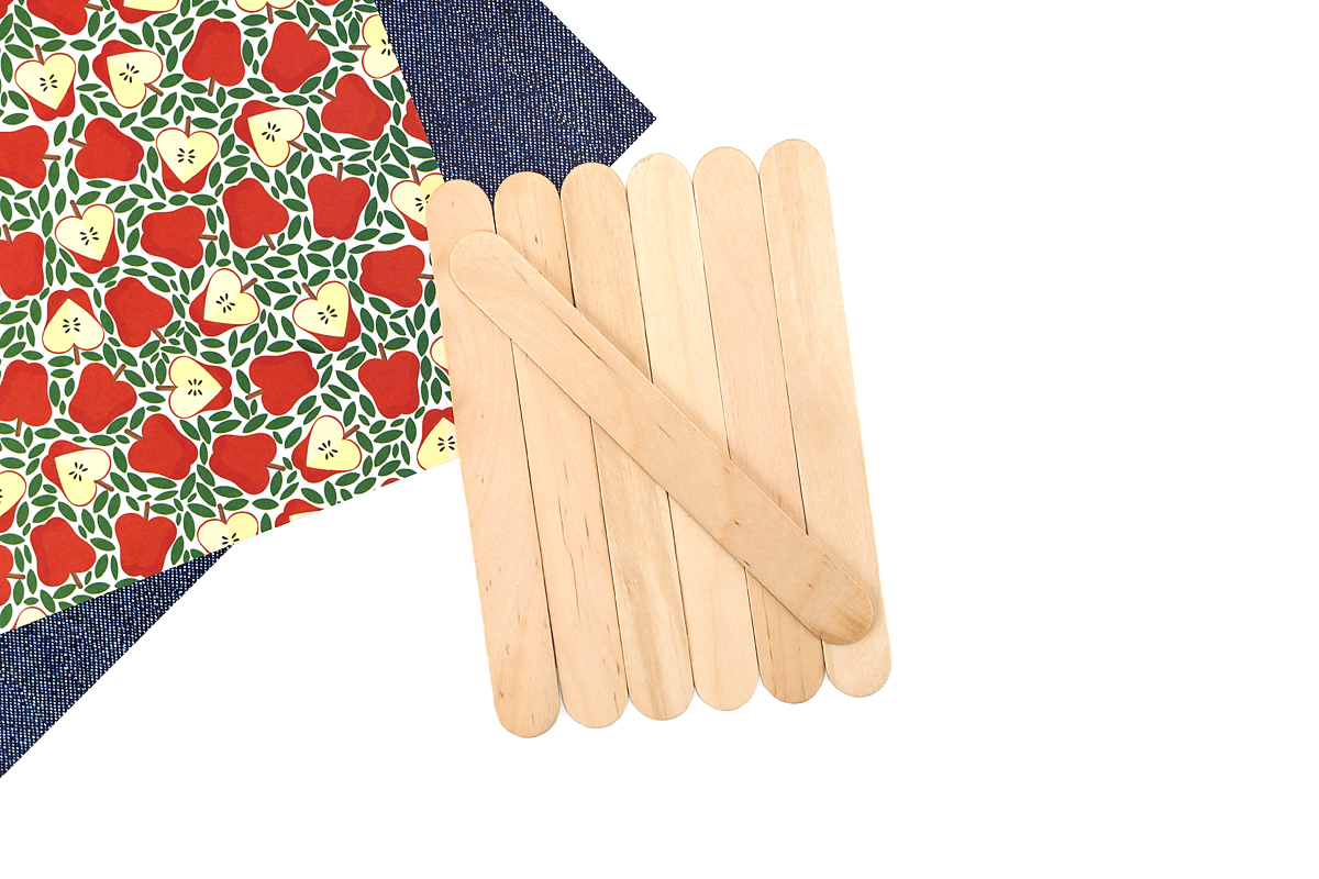 Six unpainted wooden craft sticks arranged side by side with one stick laid diagonally on top, supplies for a popsicle stick apple craft.