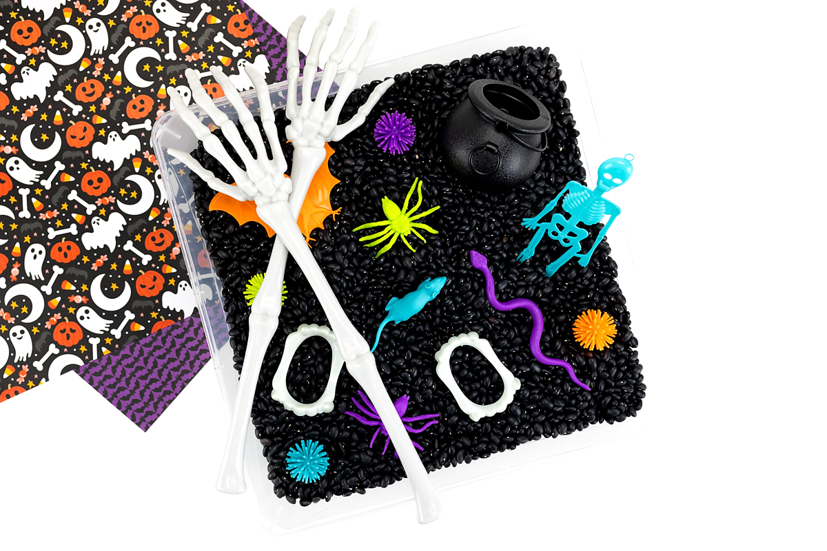 Halloween sensory bin with skeleton tongs.