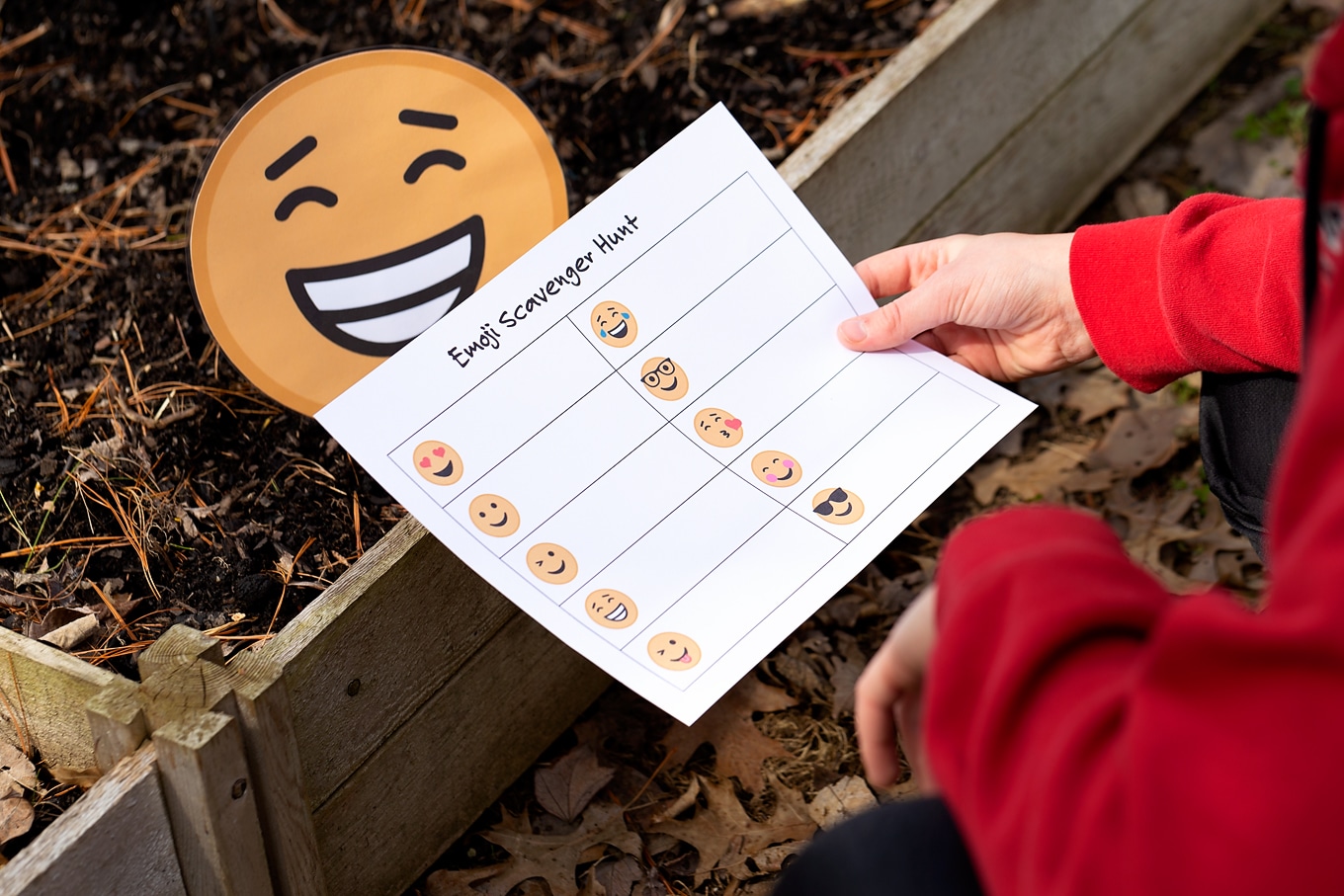 Child Holding Paper That Reads Emoji Scavenger Hunt