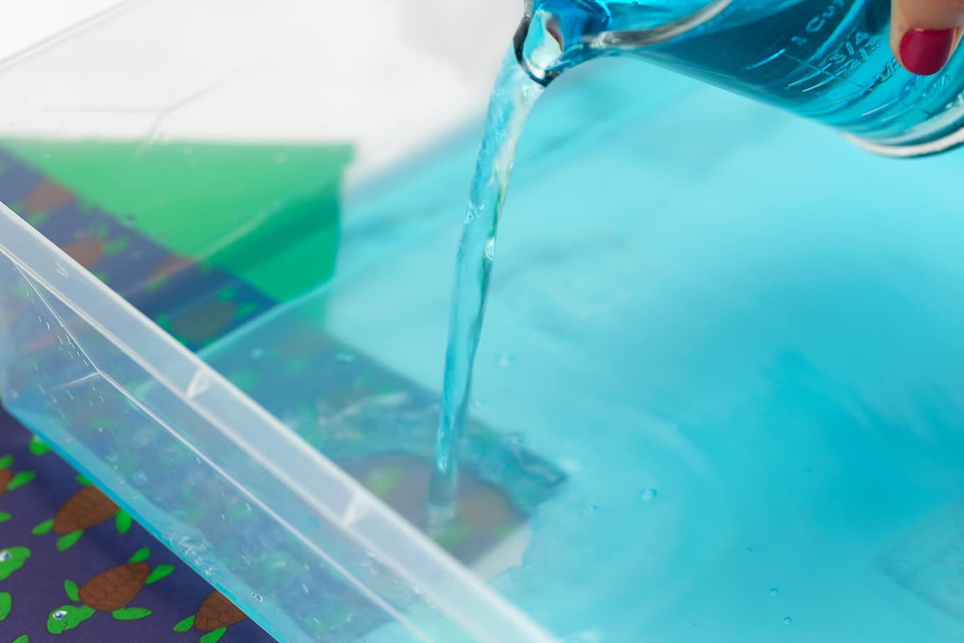 Blue Water Being Poured into a Sensory Bin Blue Water Being Poured into a Sensory Bin