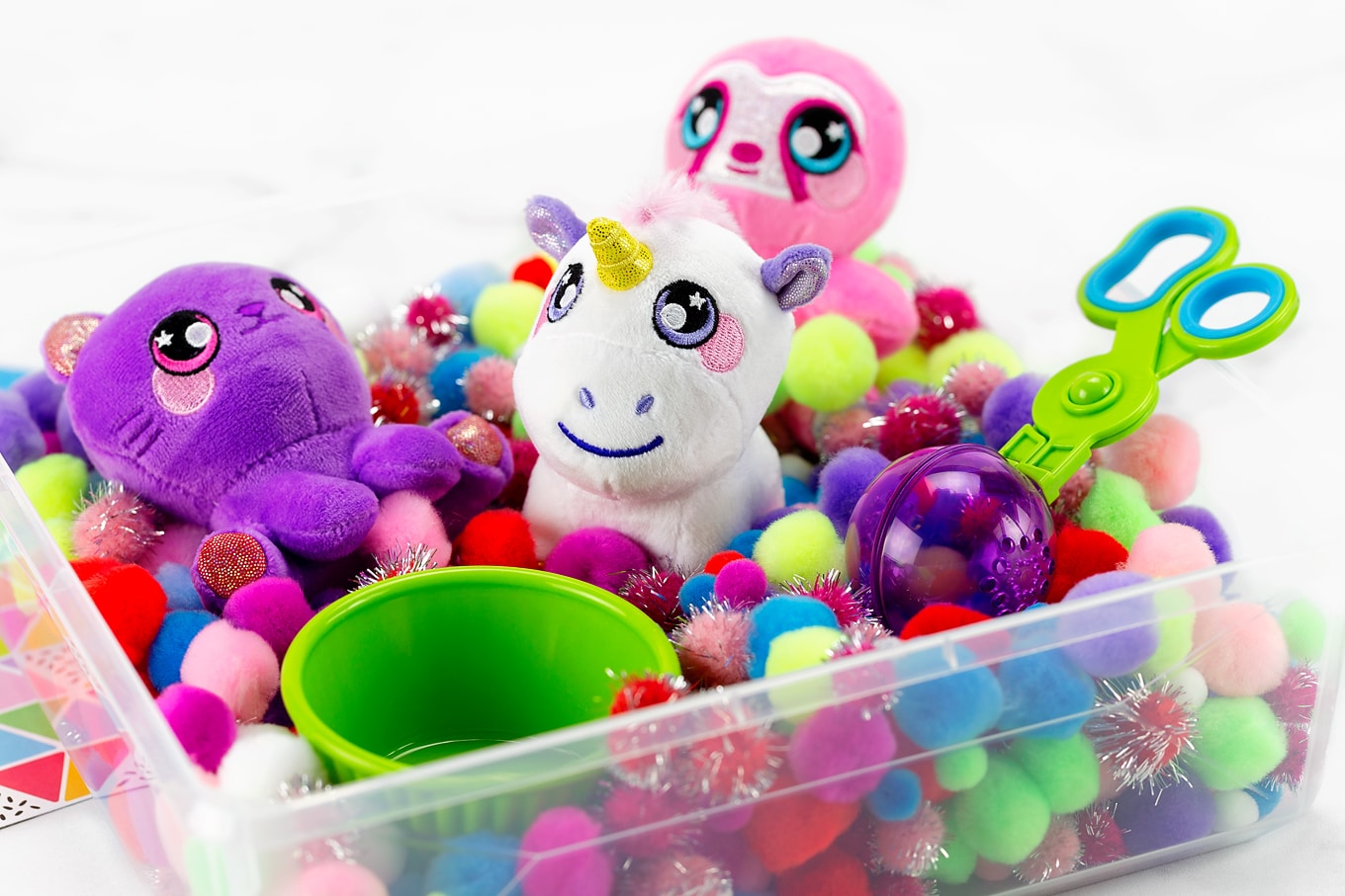 Squeezamals in a Pom Pom Sensory Bin With Cup and Scoopers