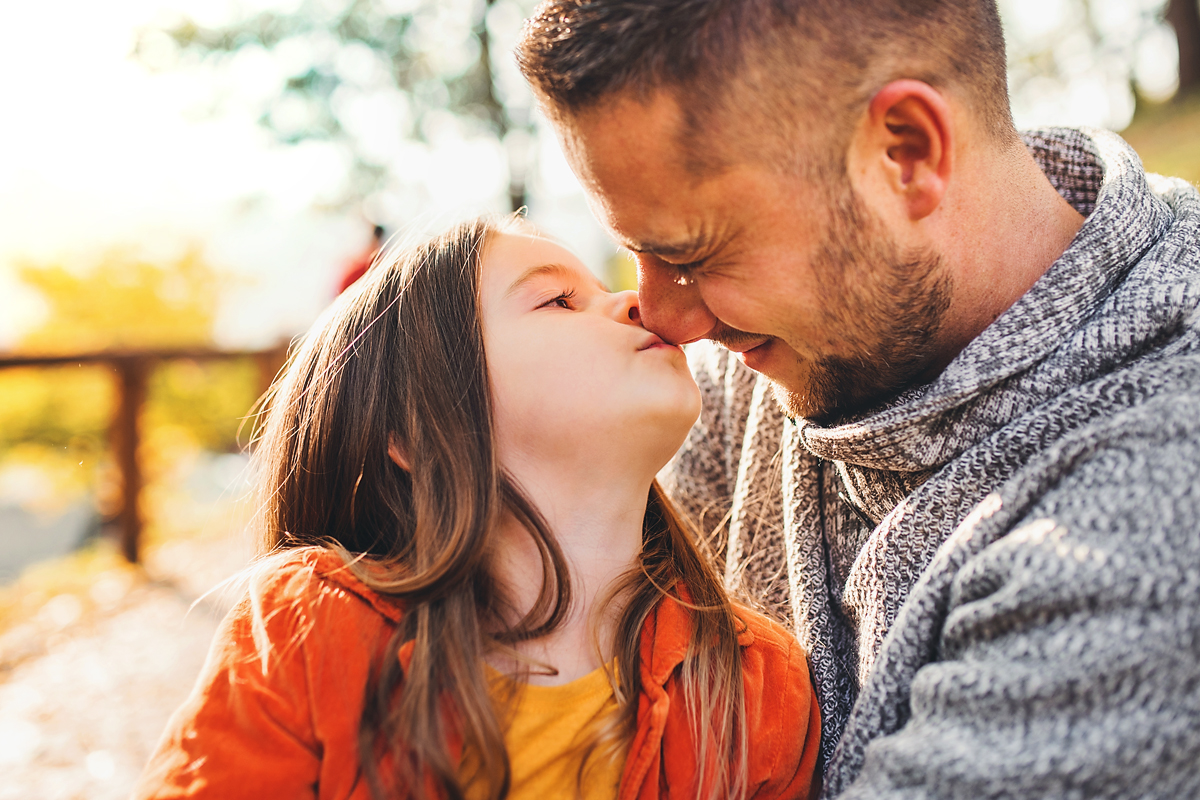Daughter and father sharing affection outdoors. 