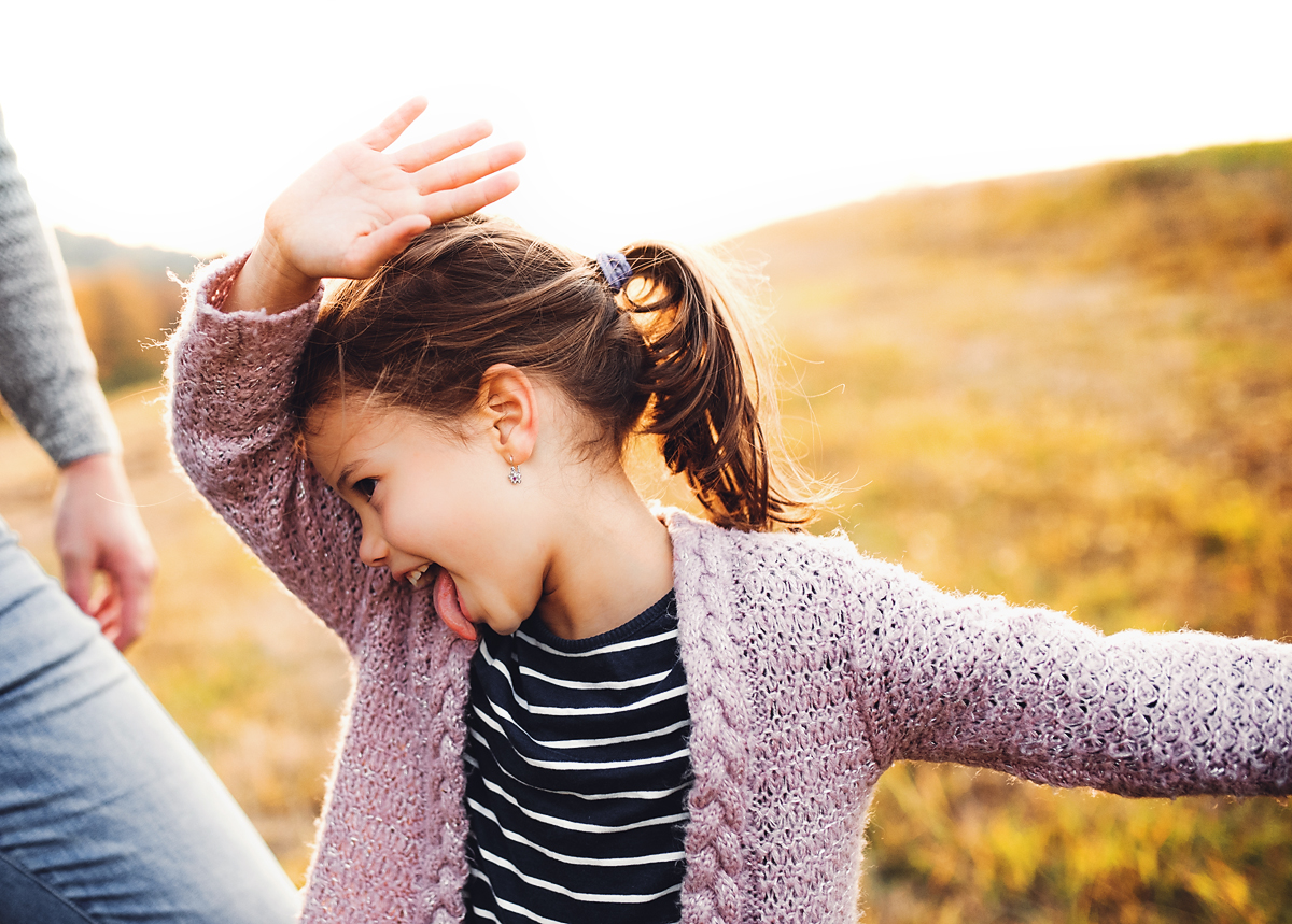 Little girl laughing outdoors with her family.