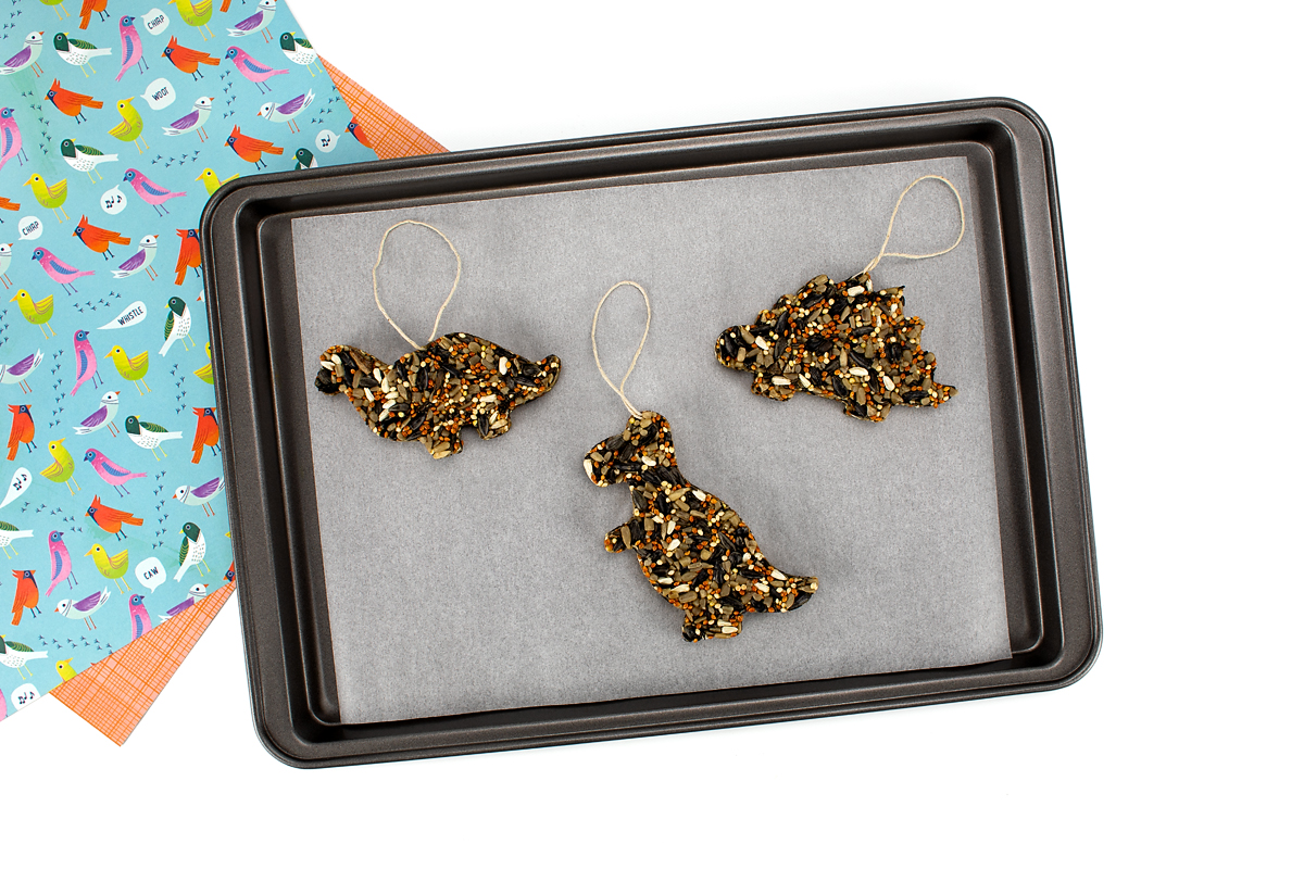 Three finished vegan birdseed ornaments drying on a cookie sheet.