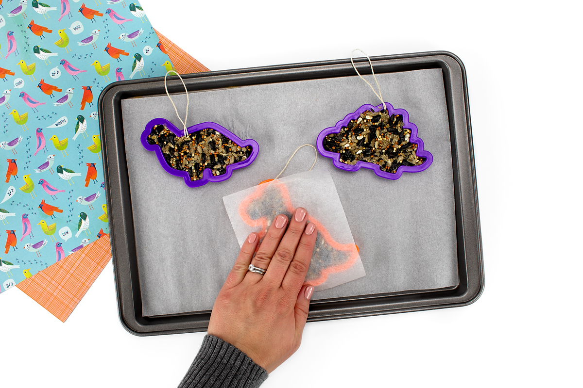 Pressing the birdseed tightly into a cookie cutter to make birdseed ornaments.