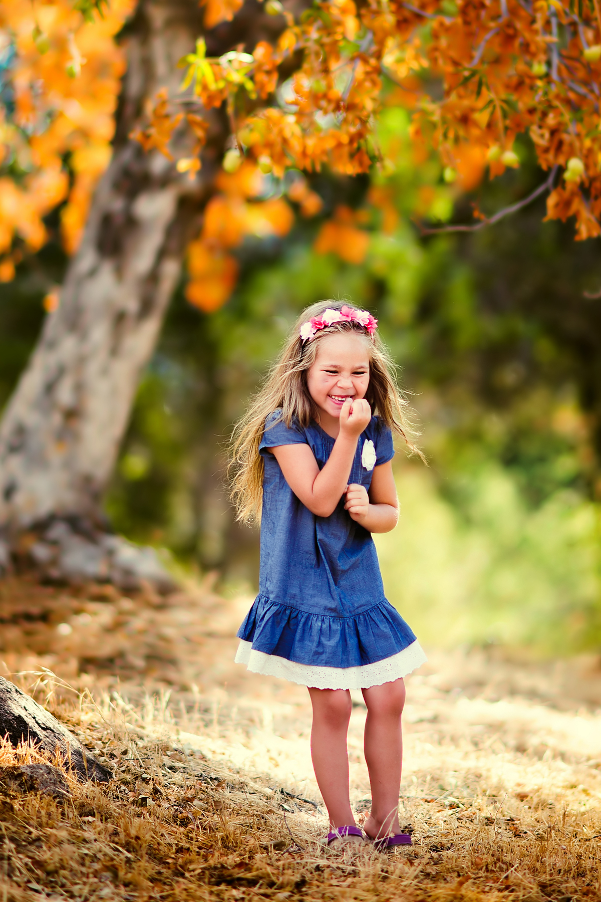 Child laughing in a fall forest.
