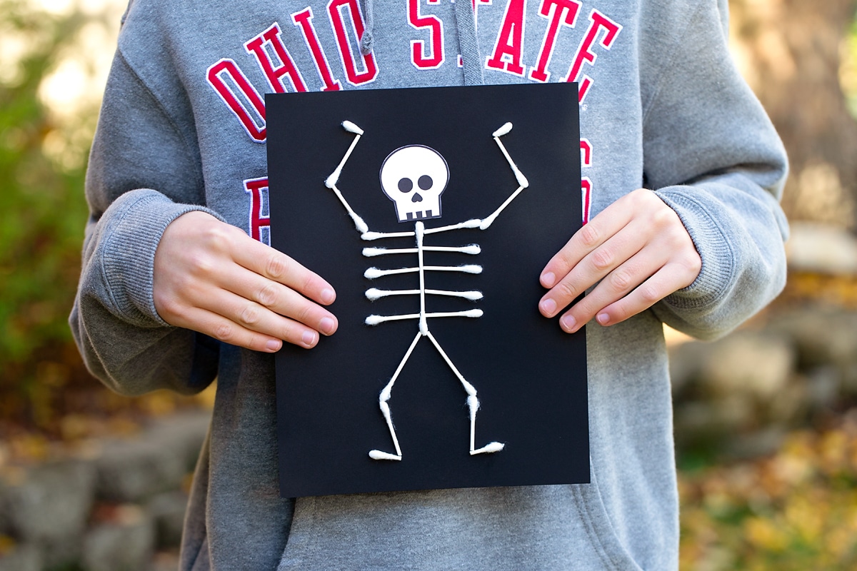 Child holding skeleton craft.