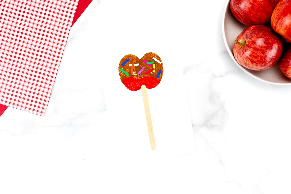 The red Caramel Apple Craft completed, with a bowl of apples in the upper right corner.