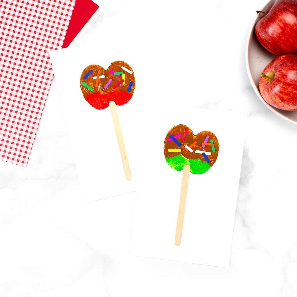 Vibrant red and green caramel apple craft, perfect for a fun and delicious autumn activity for kids, with a bowl of apples in the upper right corner.