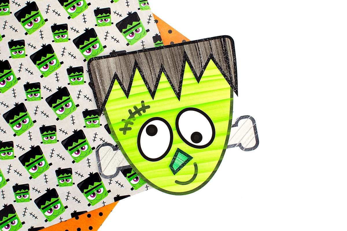 Green Frankenstein Craft displayed on top of Halloween scrapbook paper.