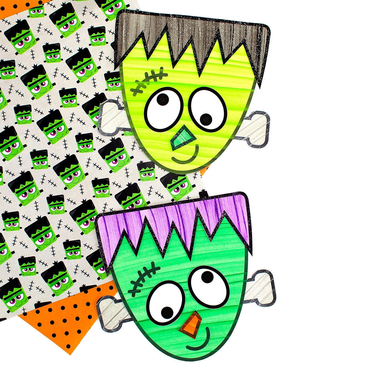 Two Frankenstein Crafts laying on top of Halloween scrapbook paper.