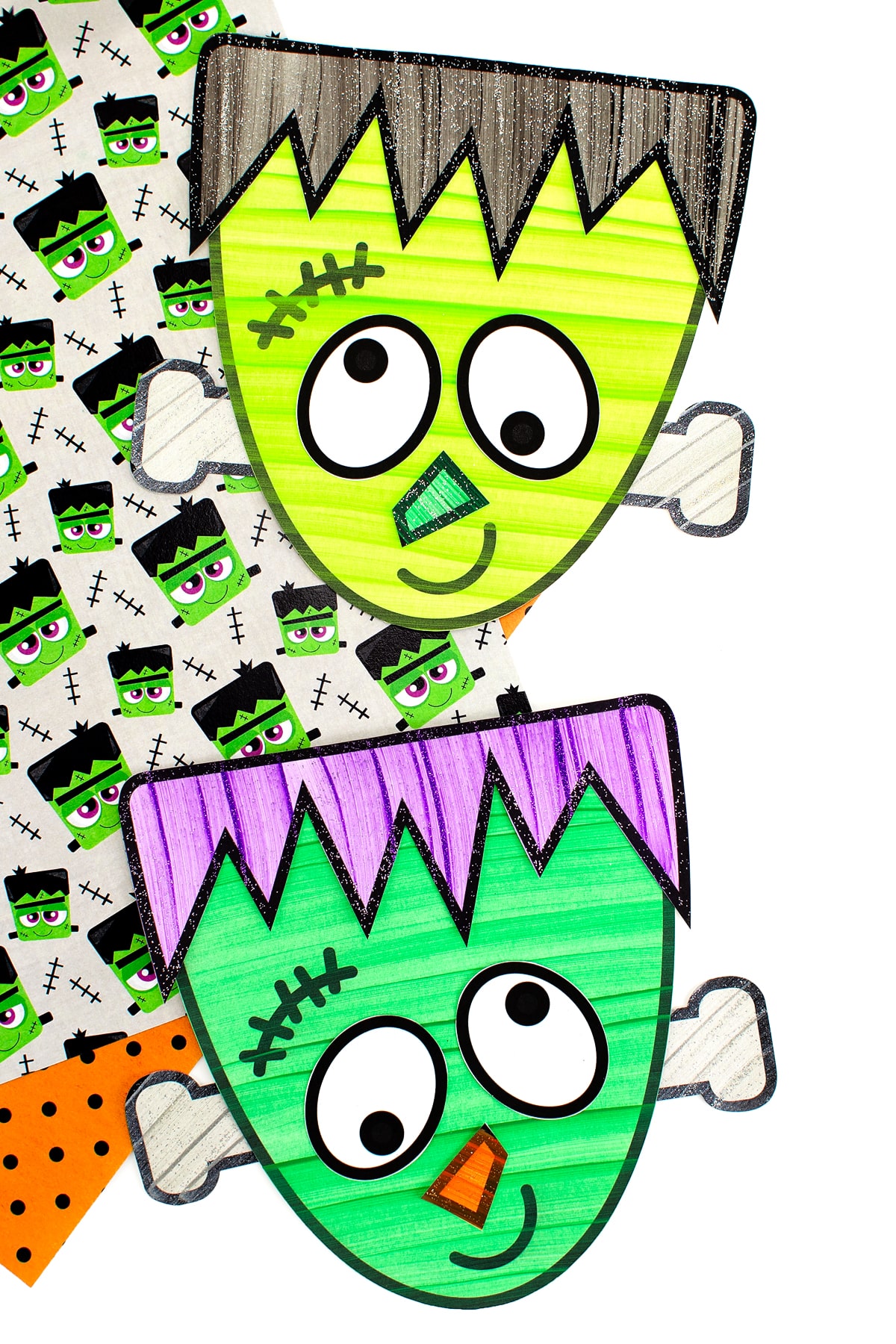 Two finished Frankenstein crafts displayed on top of Halloween scrapbook paper.