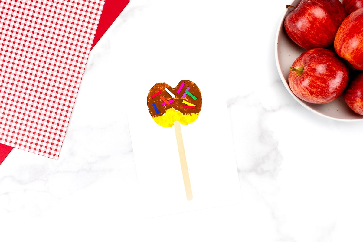 Yellow Caramel Apple Craft with a bowl of apples in the upper right corner.