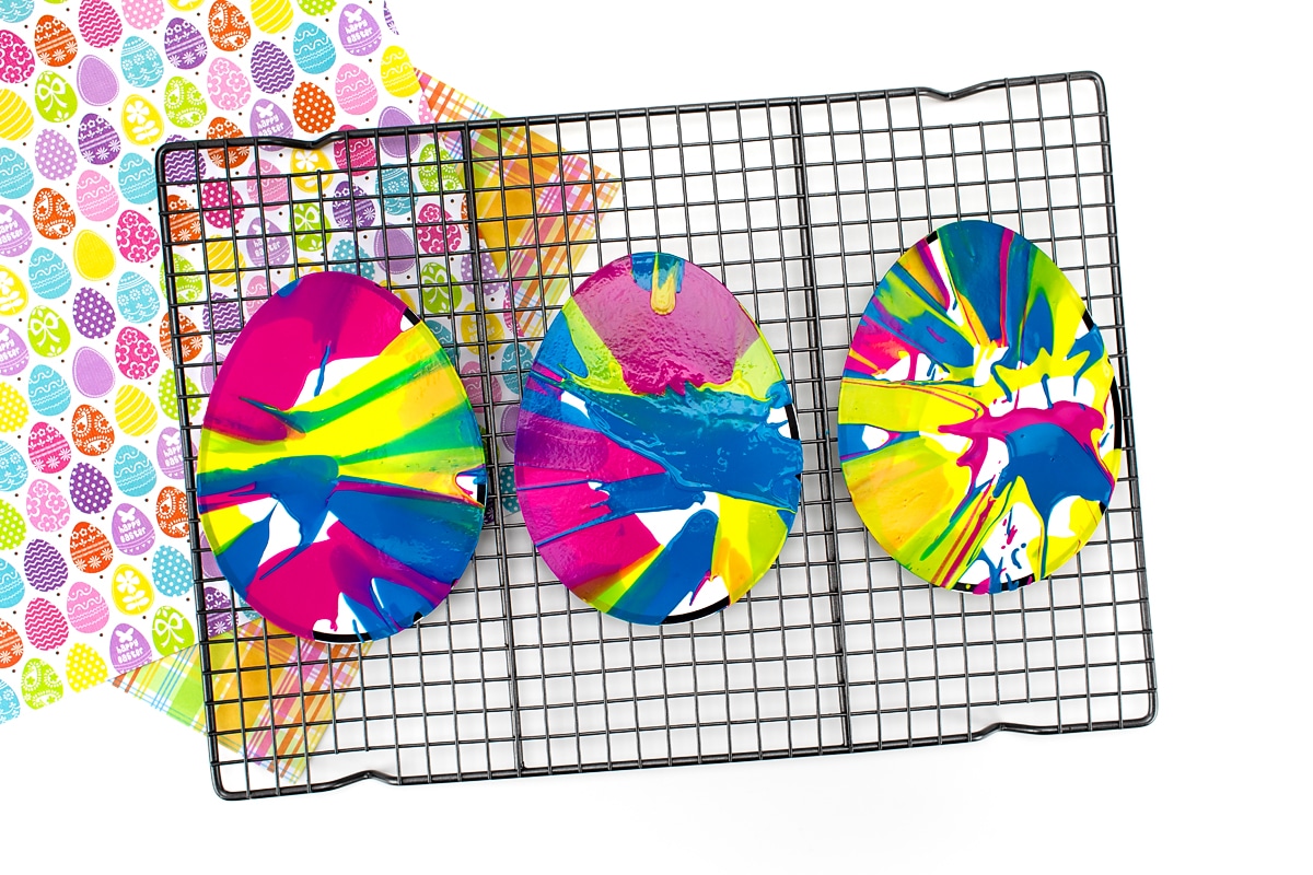 Three painted Easter eggs drying on a rack.