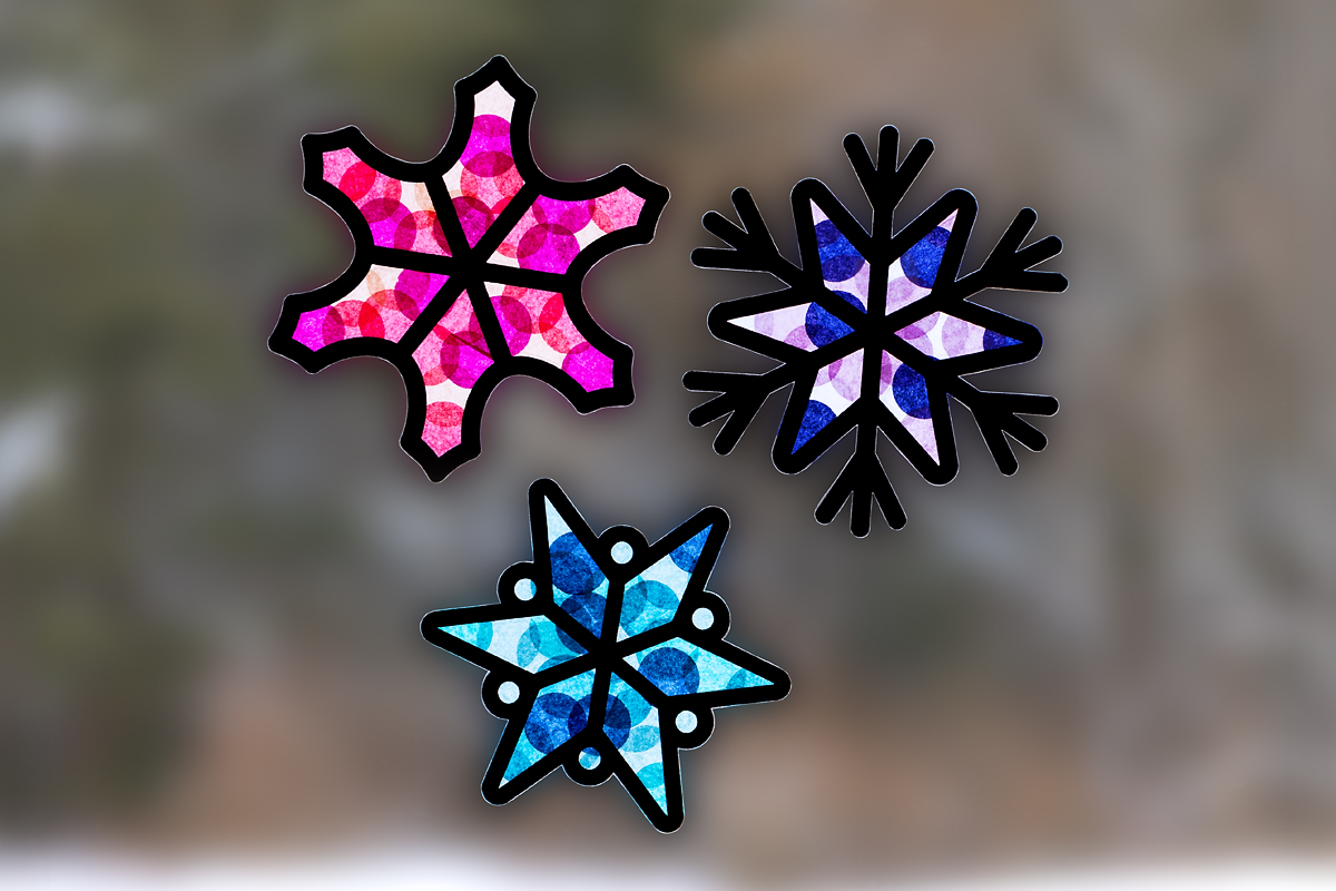Three snowflake suncatchers for kids hanging on a window.