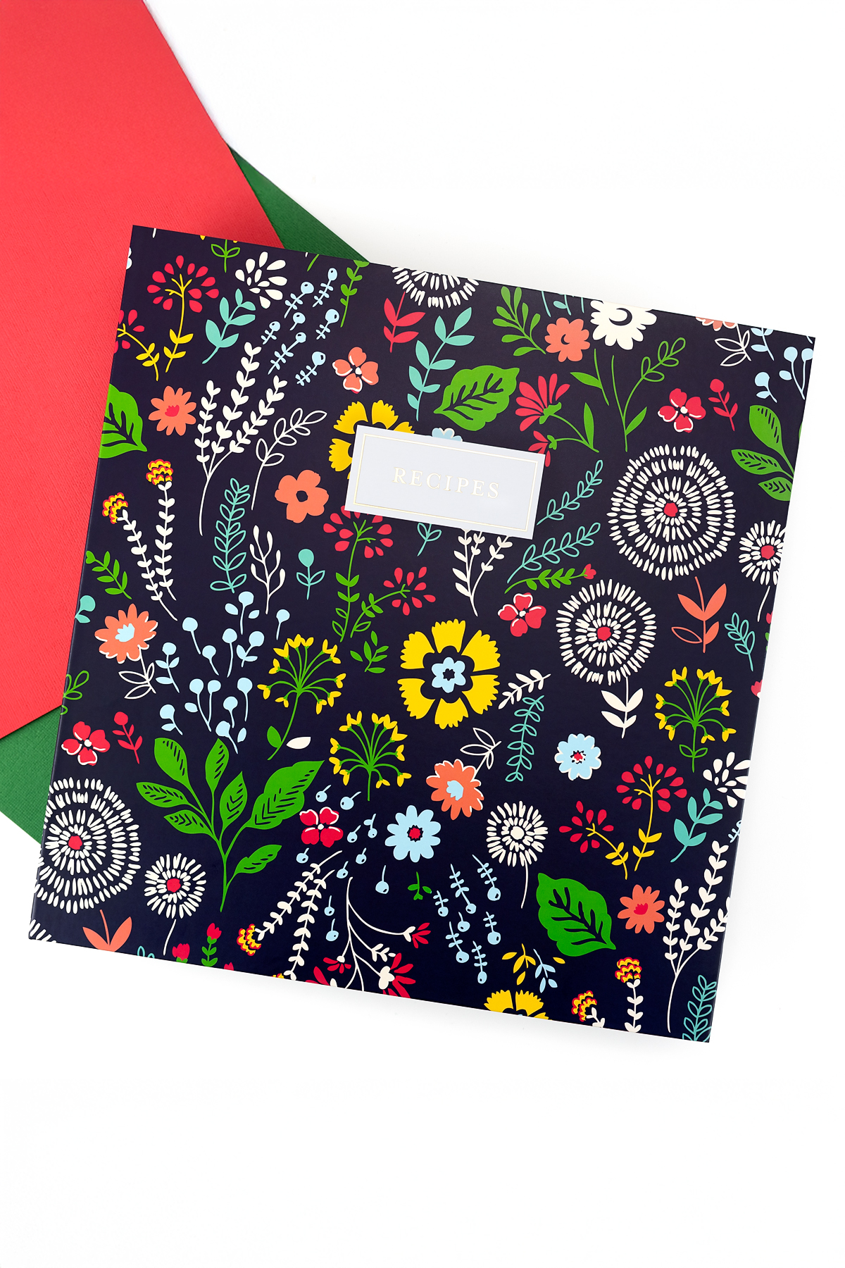 Blue floral recipe binder on coral and green paper.