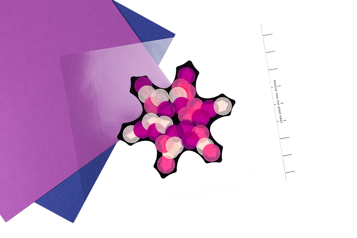 Snowflake suncatcher decorated with pink tissue paper circles.