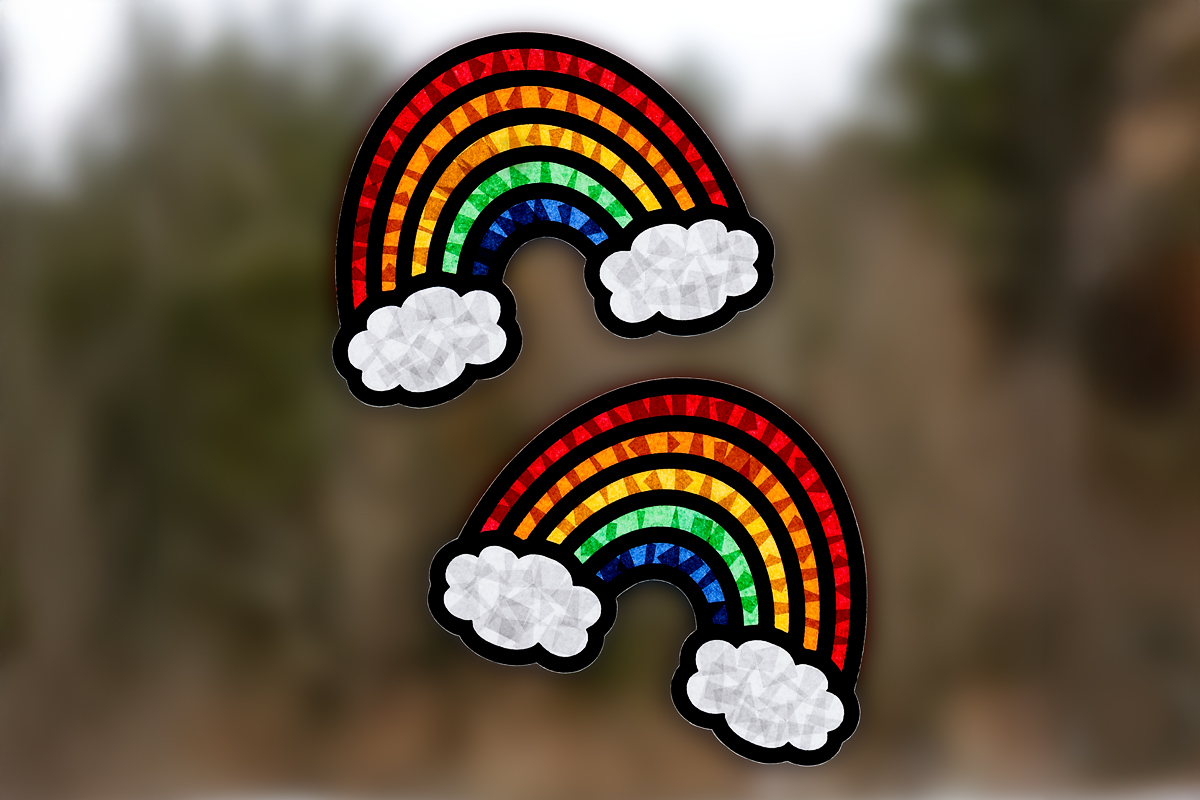 Two tissue paper rainbow suncatchers hanging in a window.