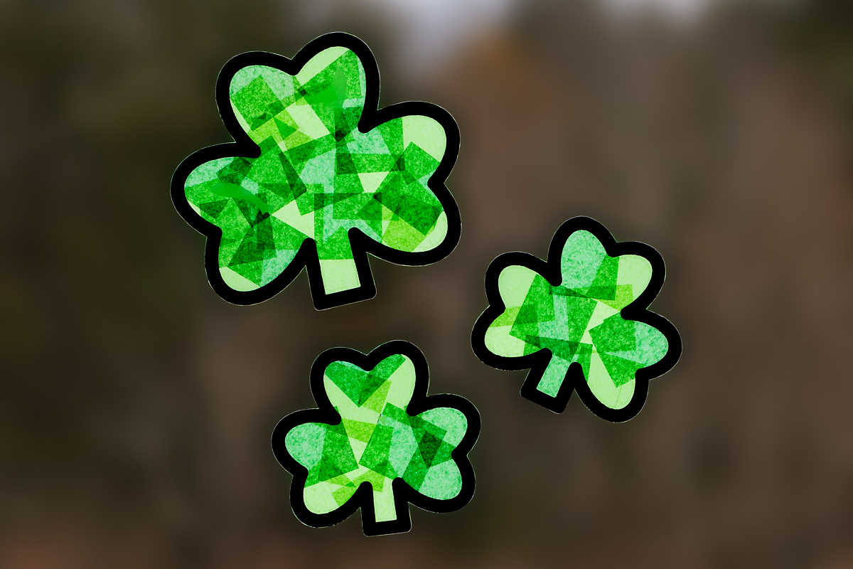 Three shamrock suncatchers (2 large and 2 small) hanging in a window.