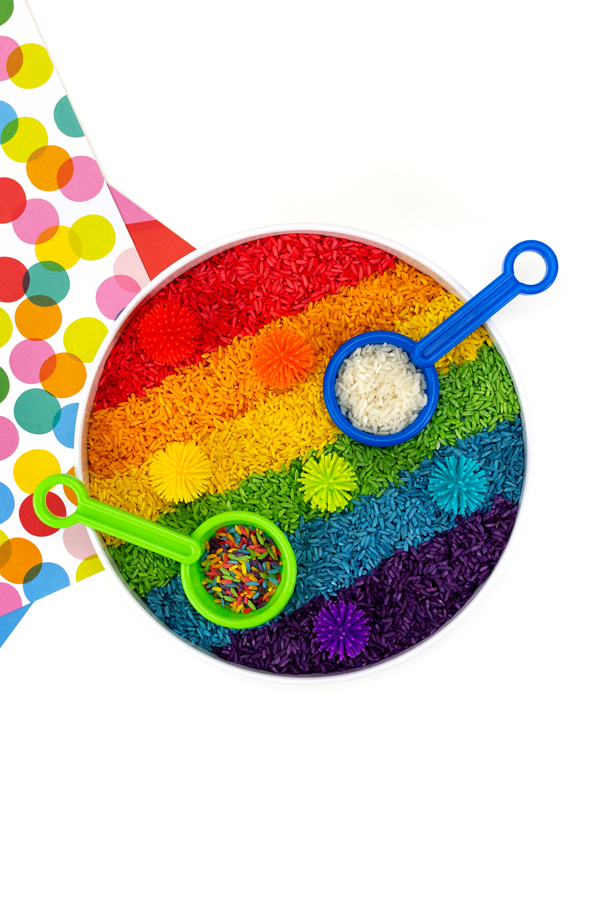 Rainbow rice in a sensory bin with mini scoops.