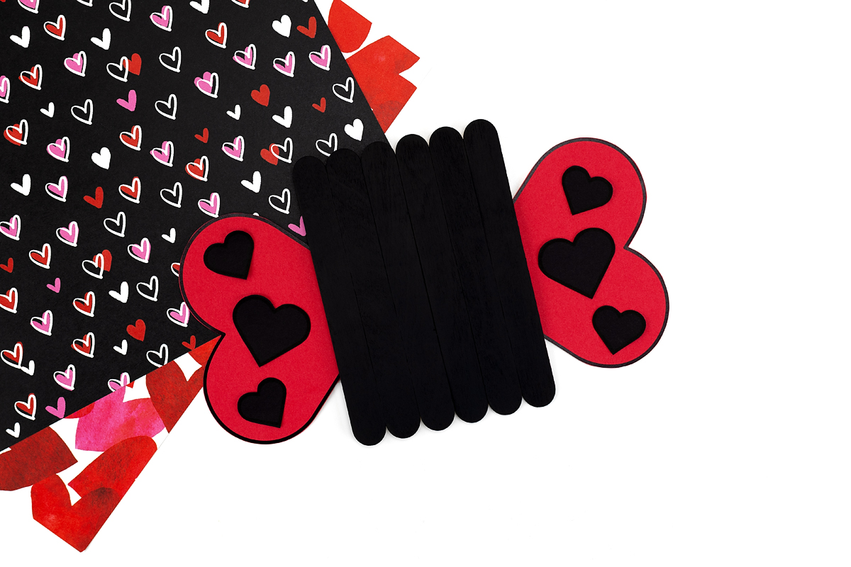 Step 6 of the popsicle stick love bug craft—glue the hearts to the wings.