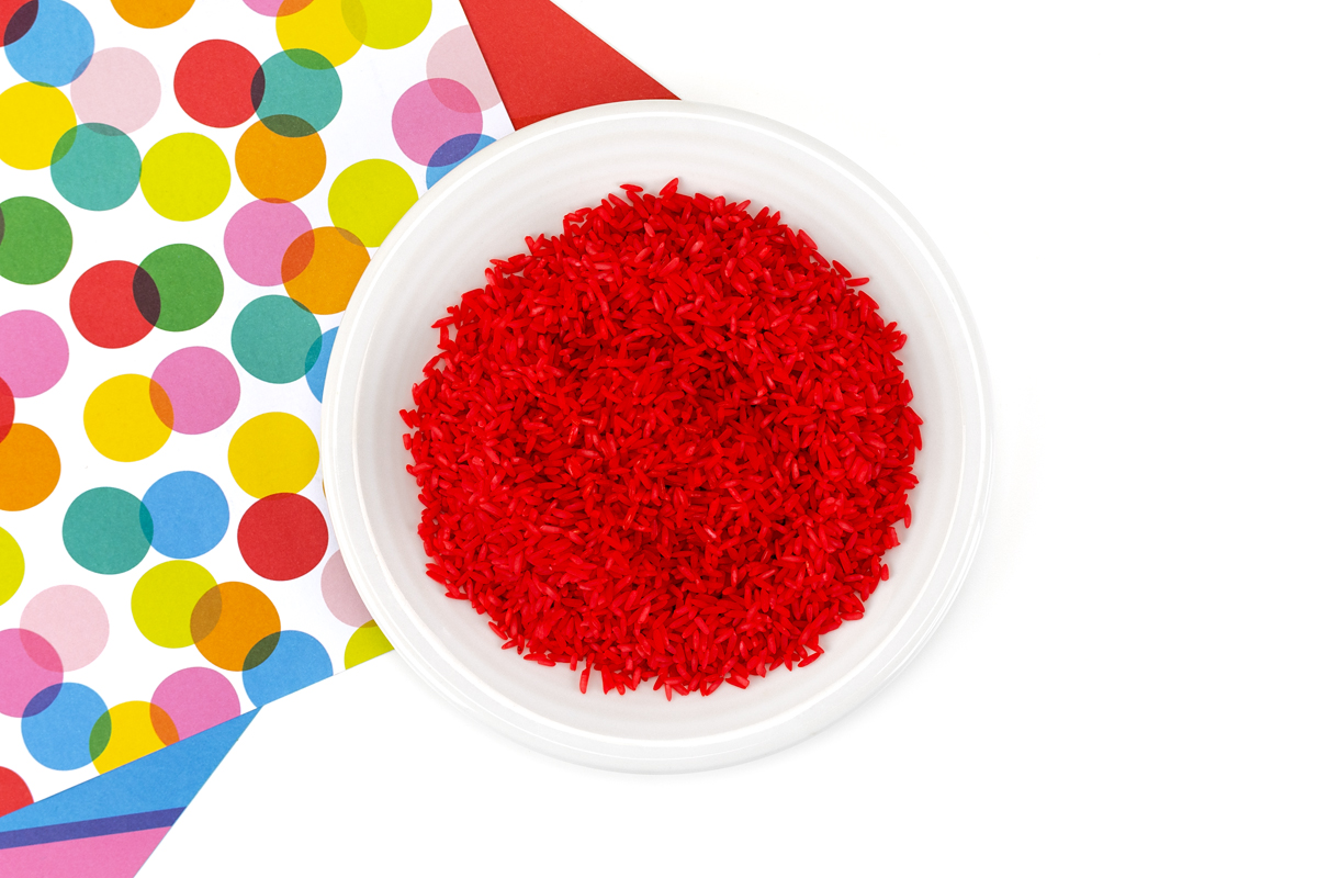 Red dyed rice drying on a plate.