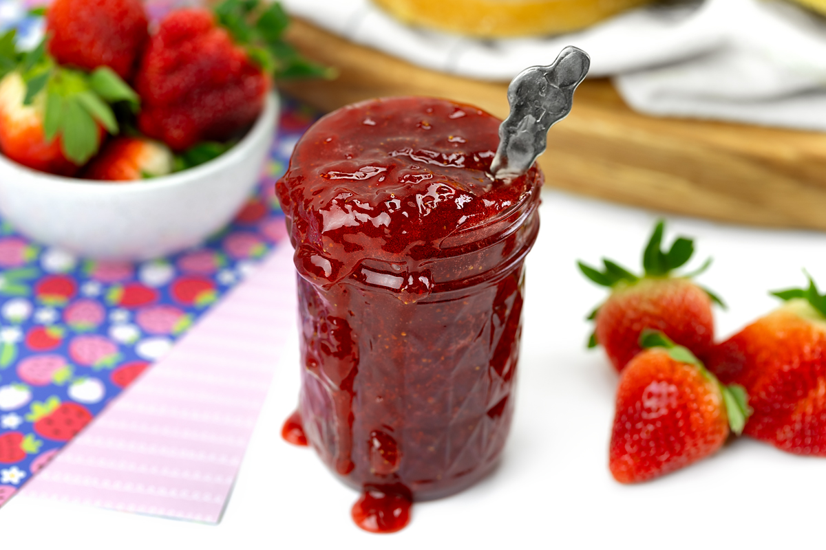 Strawberry jam overflowing from a jar.