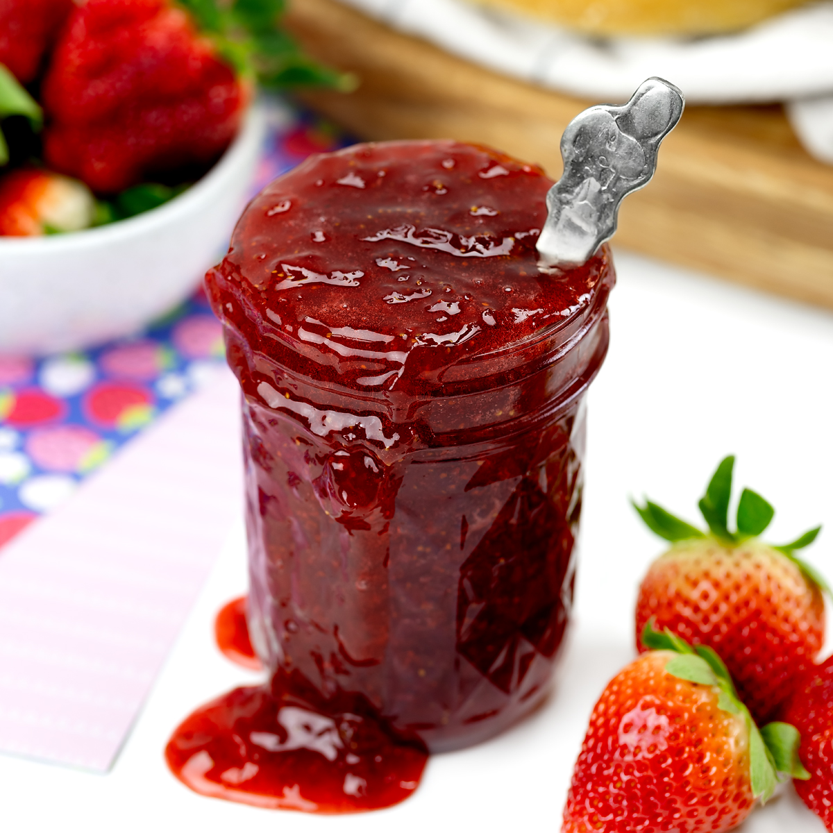 Strawberry preserves dripping out of a jar.
