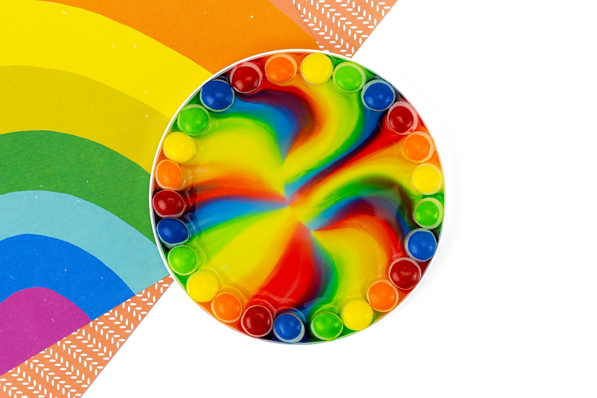Red, orange, yellow, green, and blue Skittles in water.