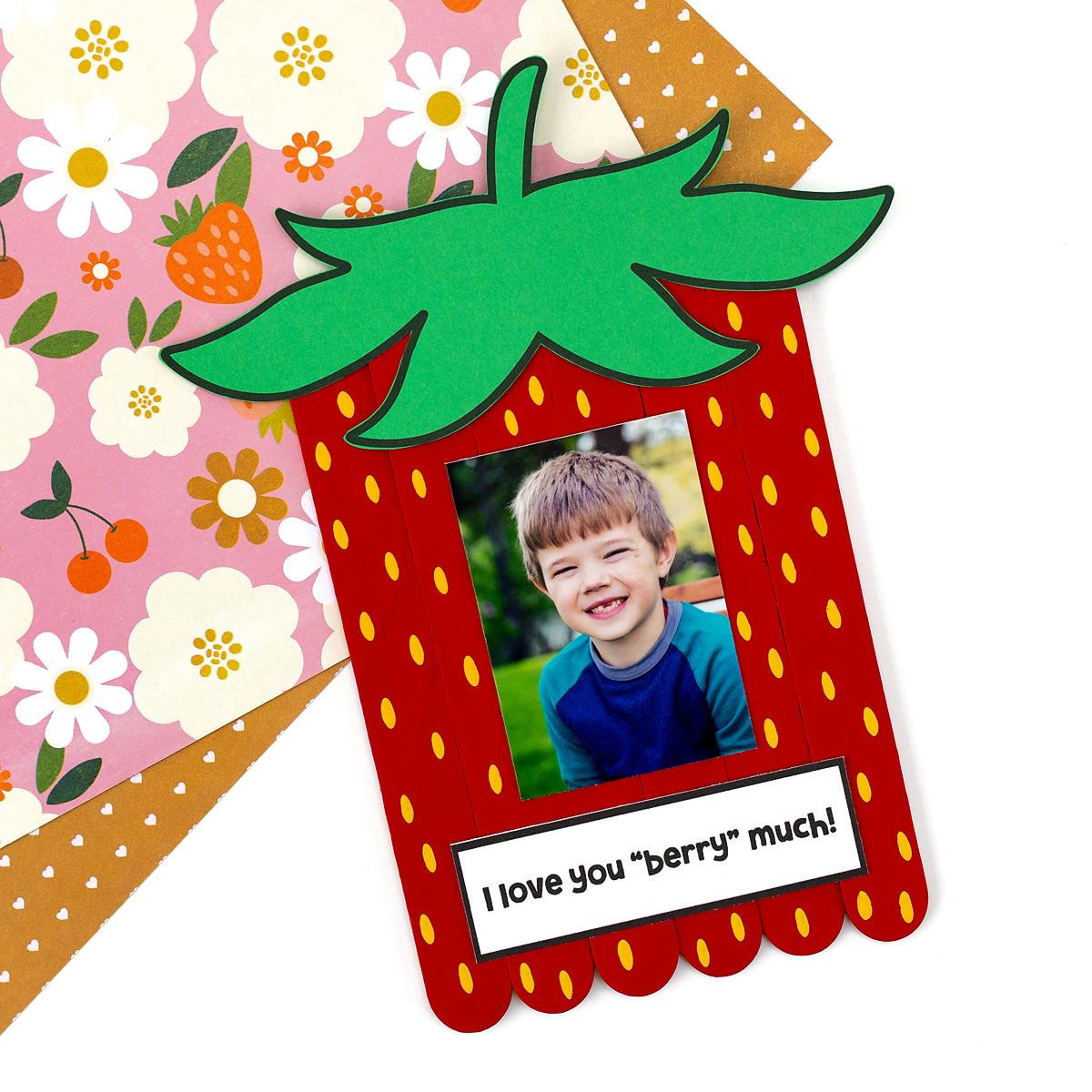 Finished Popsicle Stick Strawberry Craft on scrapbook paper.