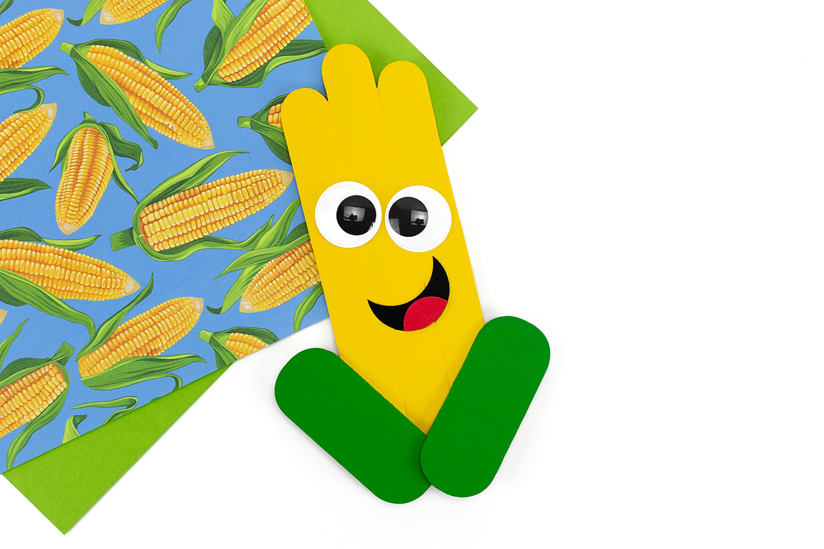 Popsicle stick corn craft with face.