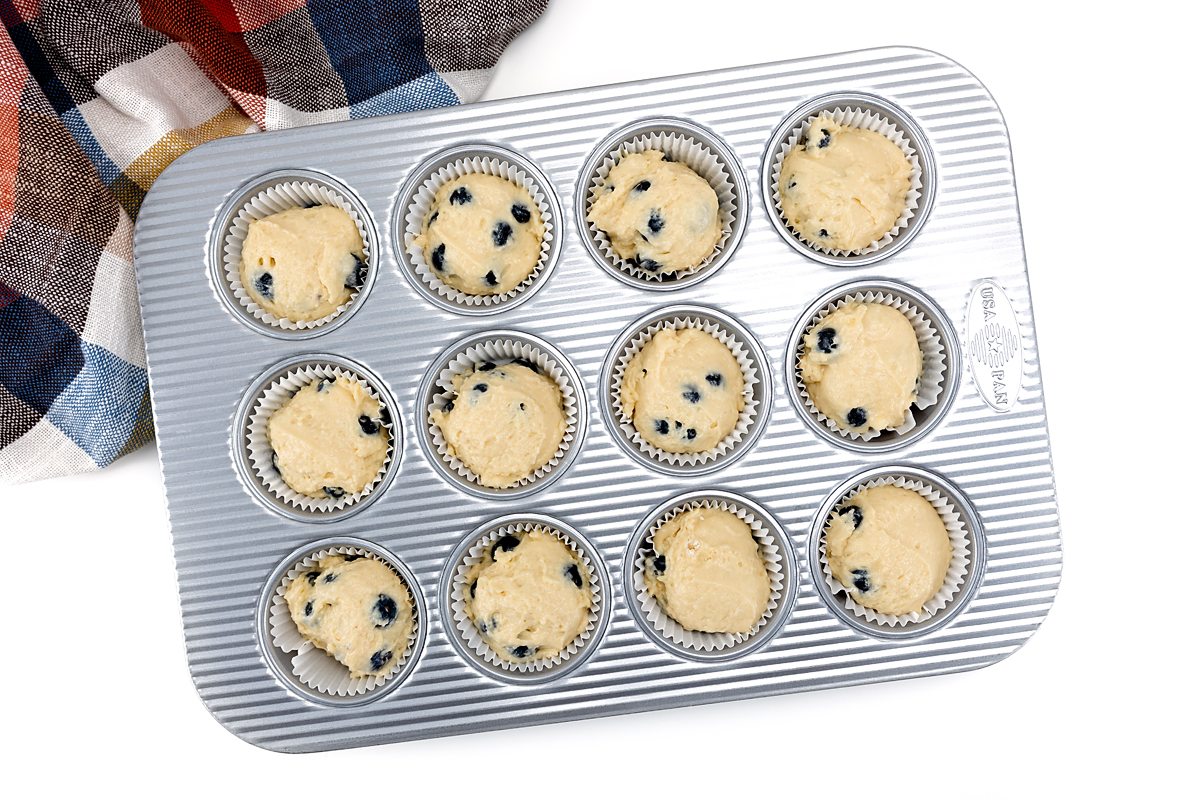 Blueberry muffin batter in muffin cups.