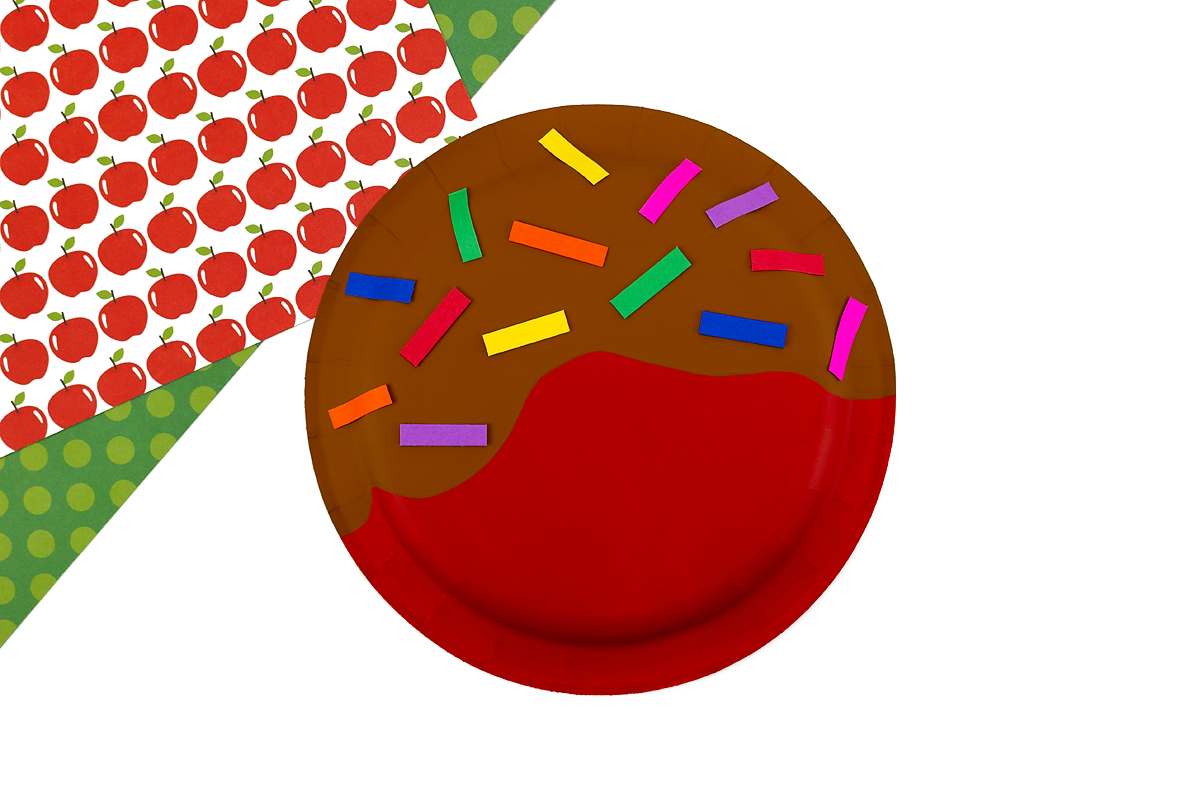 Paper sprinkles on top of a paper plate caramel apple.