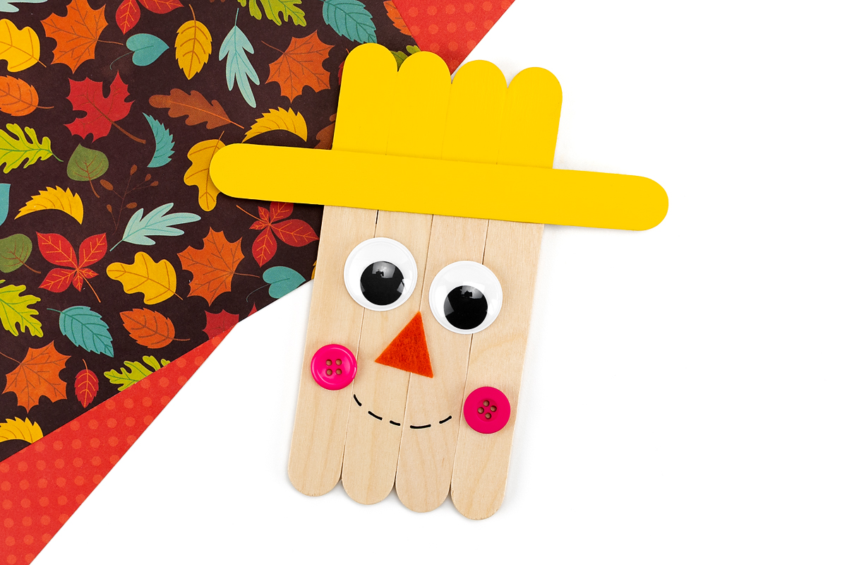 Popsicle stick scarecrow with decorated face.