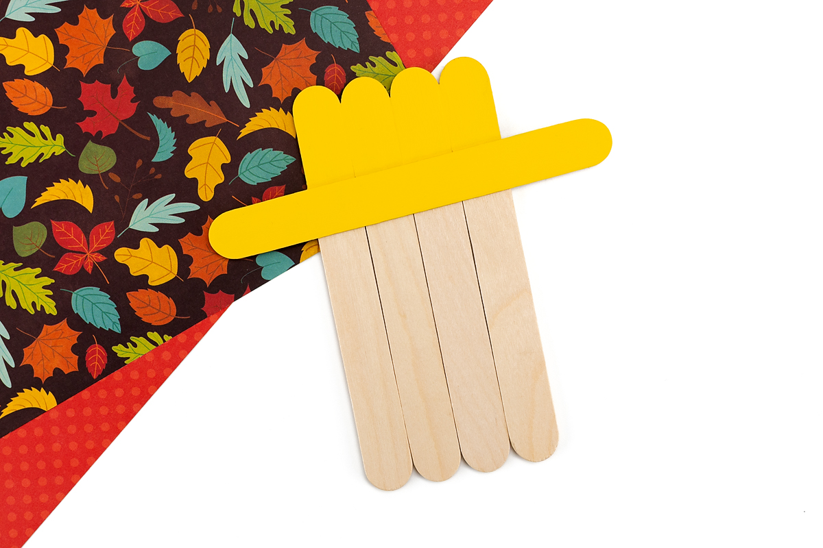 Yellow painted had on popsicle stick scarecrow.