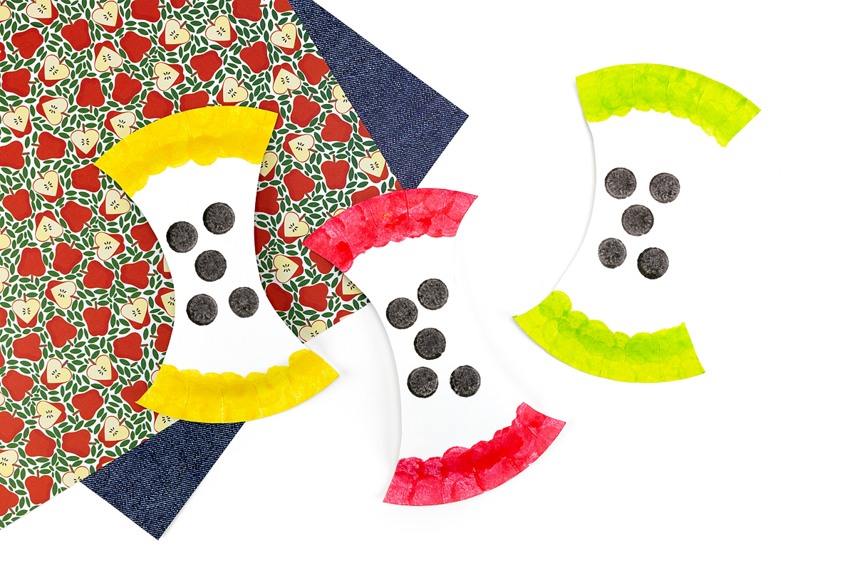 Yellow, red, and green paper plate apple cores with seeds.