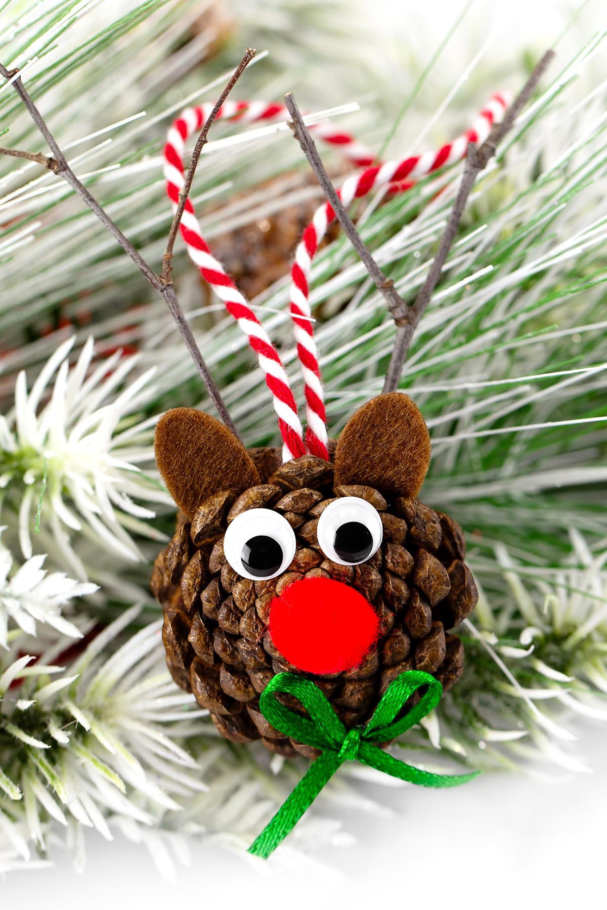 Pine cone reindeer decorated with googly eyes, pipe cleaner antlers, and a red nose.