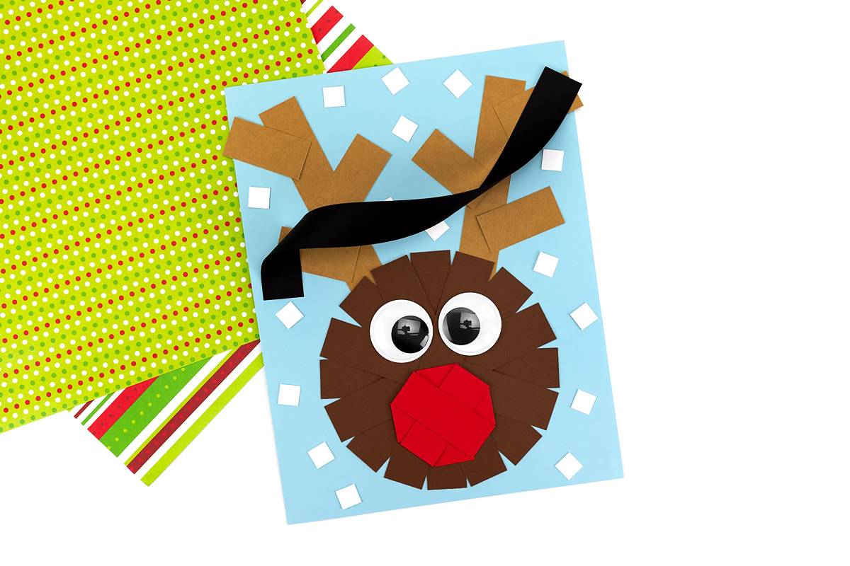 Twisting and gluing a long black paper strip across the antlers to form the base for Christmas lights.