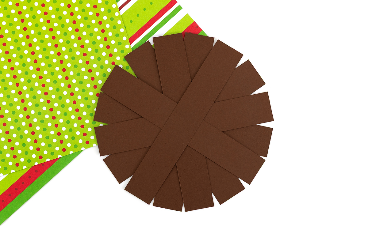 Gluing eight dark brown strips into a circle to form the reindeer’s face.