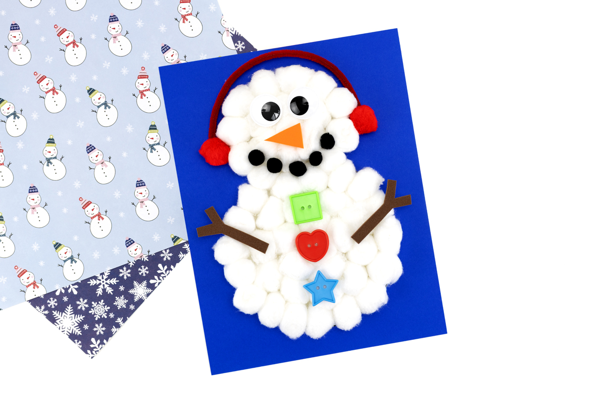 Snowman decorated with pom pom earmuffs, wiggly eyes, orange foam carrot nose, pom pom mouth, buttons, and brown foam stick arms.