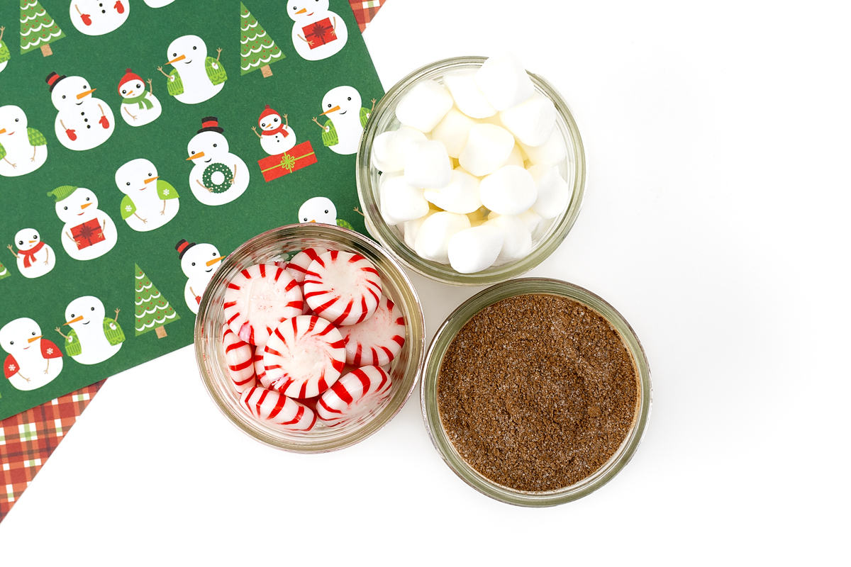 Mini mason jars filled individually with hot chocolate mix, mini marshmallows, and peppermint candies.